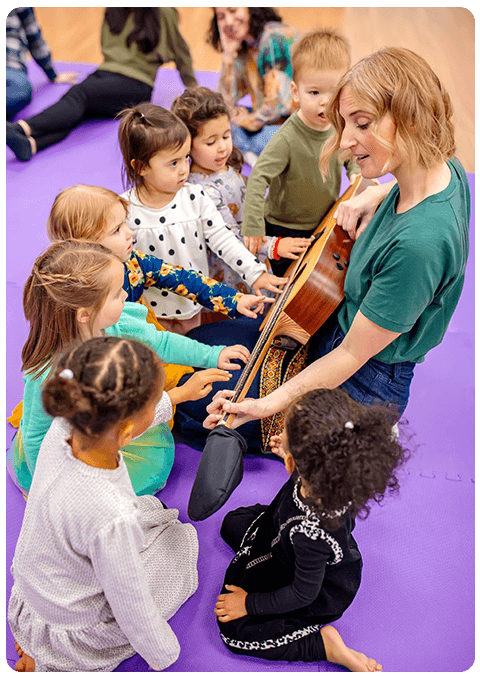 Music teacher showing young children her guitar